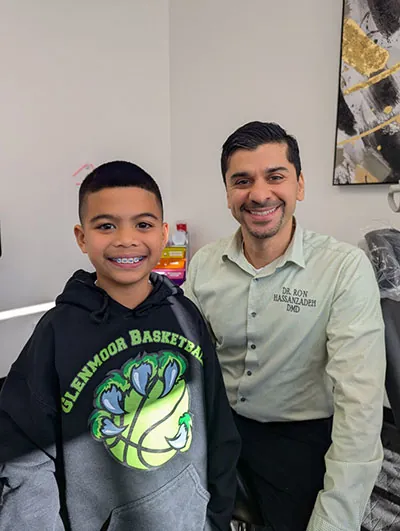 Dr. Ron Hassanzadeh sitting with a satisfied traditional braces patient